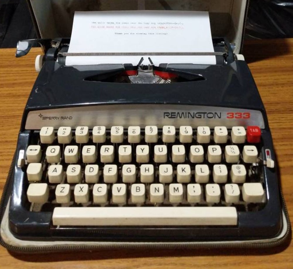 A black Remington 333 portable typewriter in its open case, a sheet of paper in the roller
