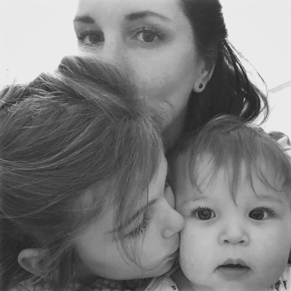 Black and white photo of Marissa with two of her children, cheek to cheek